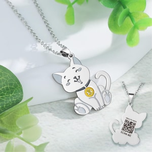 Può includere: Una collana d'argento con un ciondolo a forma di gatto bianco. Il gatto indossa un collare giallo con un'impronta di zampa. Il retro del ciondolo ha un codice QR con il testo "HEALTH INFO" e "SCAN ME".