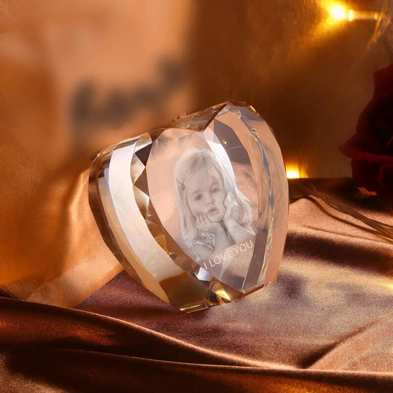 May include: A crystal heart-shaped paperweight with a 3D image of a child inside. The image is engraved with the words "I Love You".