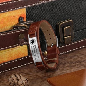Puede incluir: Pulsera de alerta m&eacute;dica de cuero marr&oacute;n con una placa plateada grabada con el texto "Allergic to All Allergic to Sulfa ICE: 348-514-2229" y un s&iacute;mbolo m&eacute;dico.