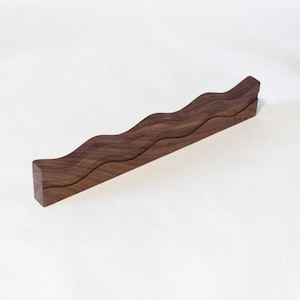 Peut inclure: Une étagère en bois foncé avec un design ondulé. L'étagère est en bois massif et a une finition naturelle.