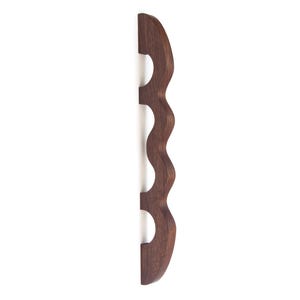 May include: A dark brown wooden wine bottle holder with a wavy design and four bottle slots.