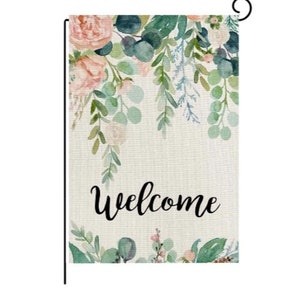 May include: A welcome garden flag featuring a watercolour design of pink and green flowers and foliage. The flag displays the word "Welcome" in black cursive writing.