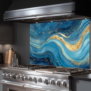 May include: A blue and gold abstract kitchen backsplash with a wavy design. The backsplash is installed behind a stainless steel gas range and under a black range hood. The design features shades of blue and gold.
