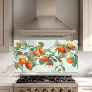 May include: A kitchen backsplash with a watercolour painting of persimmon fruit on a branch. The artwork displays vibrant orange persimmons with teal and gold leaves against a light blue and white background. The backsplash is installed above a gas hob.