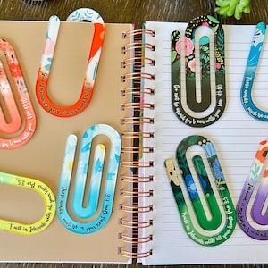 May include: A set of eight colorful floral patterned paper clips with inspirational bible verses printed on them. The paper clips are designed to hold pages in a book or journal.