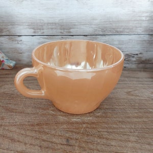 May include: A light brown ceramic teacup with a rounded shape and a single handle.