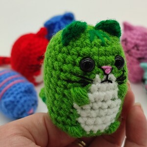 A green Amigurumi kitten, held in hand.