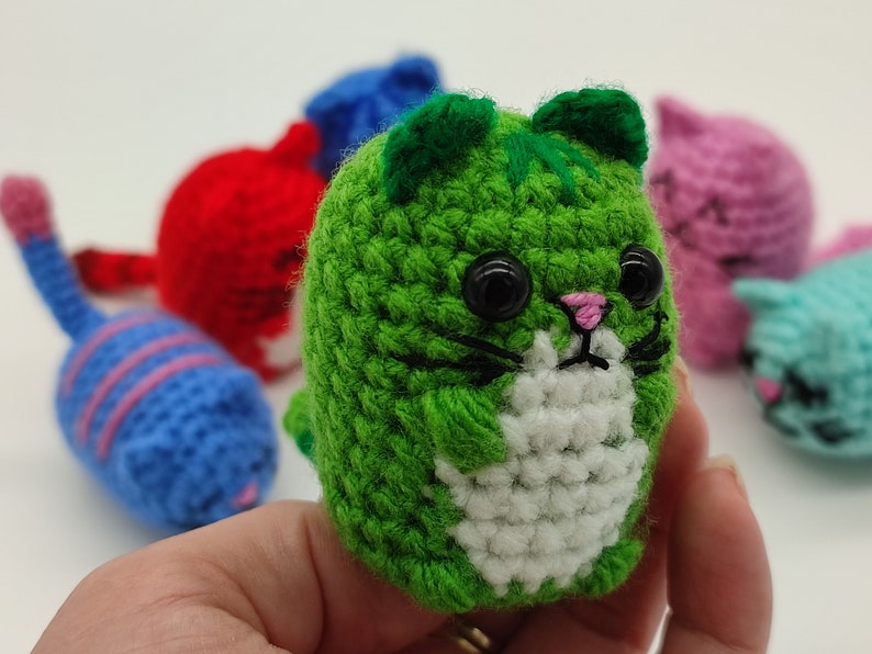 A green Amigurumi kitten, held in hand.