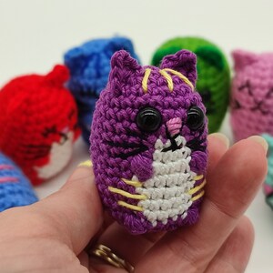 A purple Amigurumi kitten, held in hand.