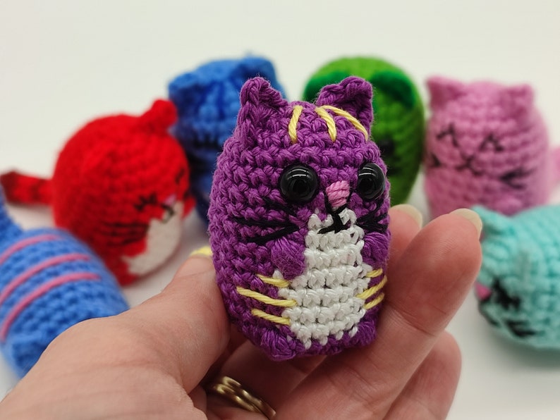A purple Amigurumi kitten, held in hand.
