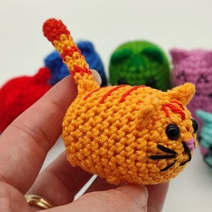 An orange Amigurumi kitten, held in hand.