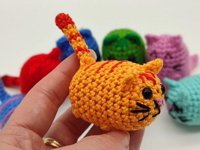 An orange Amigurumi kitten, held in hand.