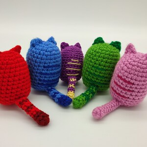 Rear view of five crocheted kittens with their tails. Red, blue, purple, green and pink.