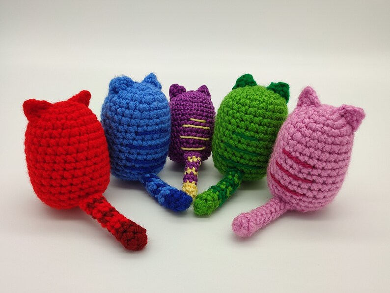 Rear view of five crocheted kittens with their tails. Red, blue, purple, green and pink.