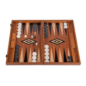 Puede incluir: Un juego de backgammon de madera con un tablero marrón y negro, fichas blancas y negras y dados. El tablero está abierto y listo para jugar.