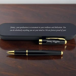 May include: A black ballpoint pen with gold-tone accents and the name Jimmy Higgins engraved on the cap. It is accompanied by a matching black rectangular case featuring the engraved message: Jimmy, your graduation is a testament to your resilience and dedication. You can do absolutely anything you set your mind to. We are forever proud of you!
