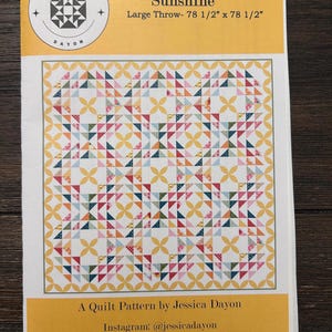 May include: A quilt pattern titled "Sunshine" by Jessica Dayon. The pattern is for a large throw, measuring 78 1/2 inches by 78 1/2 inches. The quilt design features a colorful geometric pattern with yellow, pink, blue, and white triangles.
