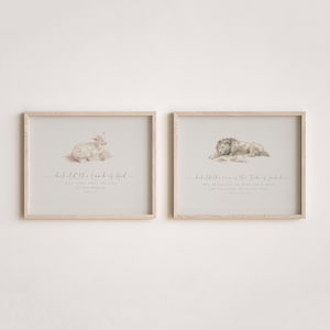May include: Two framed prints with light wood frames. One print features a lamb illustration with the text "behold the lamb of God". The other print shows a lion illustration with the text "behold the lion of the tribe of Judah".