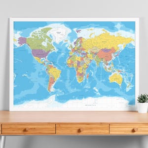 Puede incluir: Un mapa del mundo colorido enmarcado en blanco. El mapa muestra continentes y países en varios colores sobre un fondo azul océano. El mapa es detallado, mostrando nombres de países y características geográficas.