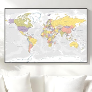 May include: A framed world map with a black border. The map shows countries in various colours, including yellow, purple, and green. Continents and oceans are labelled, set against a light grey background.