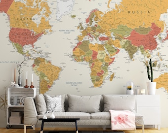 May include: A vintage-style world map wallpaper mural in beige, brown, and red tones, featuring the names of countries and continents. The map is displayed on a wall in a living room setting with a couch, coffee table, and plants.