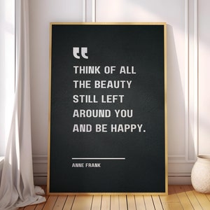 May include: Black and white typography quote on a black background with a gold frame. The quote reads "Think of all the beauty still left around you and be happy."  The quote is attributed to Anne Frank.