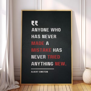 May include: A black and white motivational quote poster with gold trim. The quote reads "Anyone who has never made a mistake has never tried anything new."  The quote is attributed to Albert Einstein.