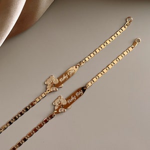 May include: Two gold bracelets with bear charms and engraved plates that read "Baby Girl" and "Baby Boy".