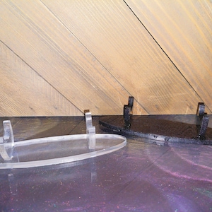 May include: Two oval-shaped display stands, one clear acrylic and one black, with raised prongs for holding items.