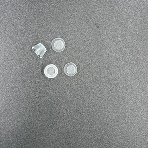 May include: Four clear plastic bottle stoppers with a small white filter inside each stopper.
