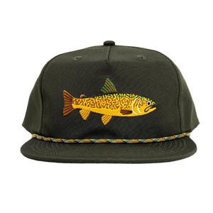 May include: A dark green baseball cap with a brown, yellow, and green embroidered trout on the front. The cap has a rope-like band around the crown.