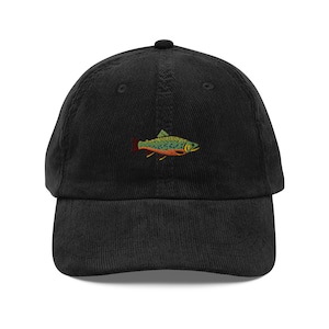 May include: Black corduroy baseball cap with a colorful embroidered fish design. The fish features green, orange, and red details. The cap has a curved brim and an adjustable strap.