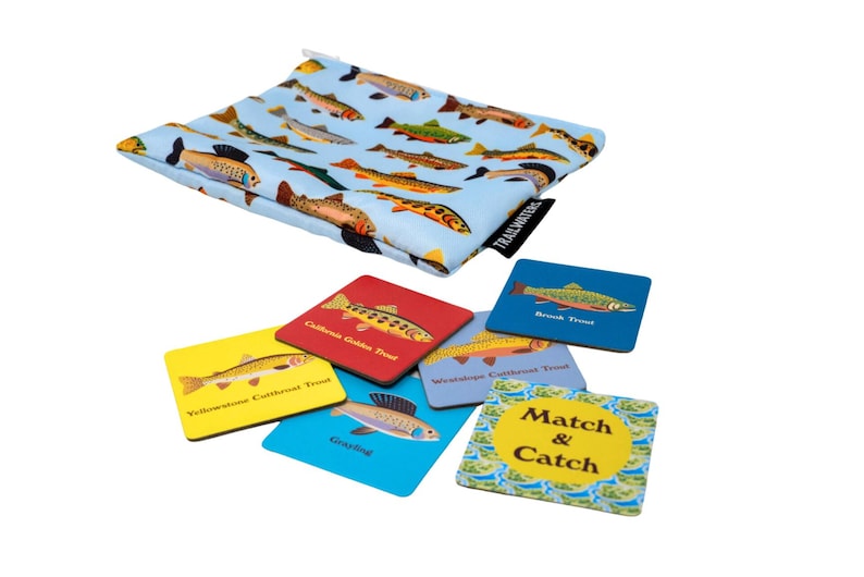 May include: A set of six colorful square cards with images of different types of trout and the words "Match & Catch" on one card. The cards are in a blue drawstring bag with a pattern of trout.