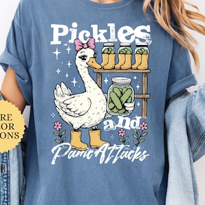 May include: A white ceramic mug with a black handle and the text "But First, Coffee" in a black, bold font. The mug is on a white surface. The mug is approximately 4 inches tall.