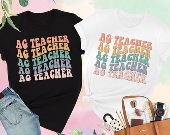May include: Two t-shirts, one black and one white, with the text "AG TEACHER" repeated five times in a rainbow of colors. The text is in a retro font style.