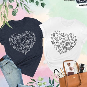 May include: Two t-shirts with a heart-shaped design made up of science-related icons. The shirts are in navy blue and white. The text on the shirts reads "E=MC2".