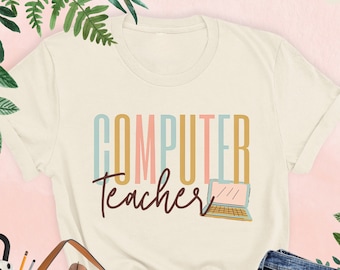 Może przedstawiać: Beżowa koszulka z napisem "COMPUTER Teacher" w kolorowych literach i małą ilustracją laptopa.