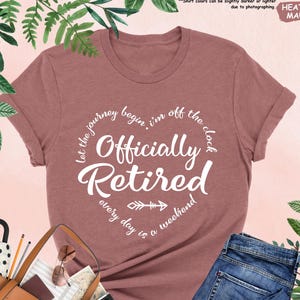 Puede incluir: Una camiseta de color malva heather con el texto "Let the journey begin. I'm off the clock. Officially Retired. Every day is a weekend." impreso en blanco.