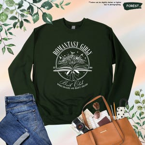 May include: A dark green sweatshirt with a white graphic design of a book with flowers and the text "Romantasy Girl Book Club Est 1969 Where Dragons and Hearts Collide"