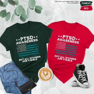a couple of t - shirts sitting next to a cup of coffee