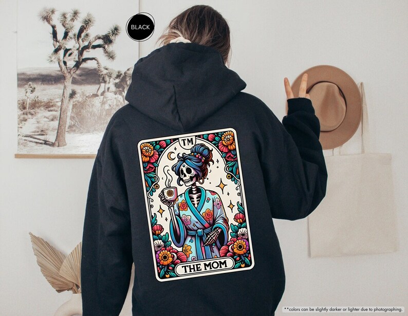 a person wearing a black hoodie with a picture of a skeleton on it