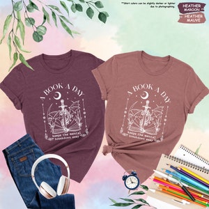 two t - shirts on a table with headphones and a notebook