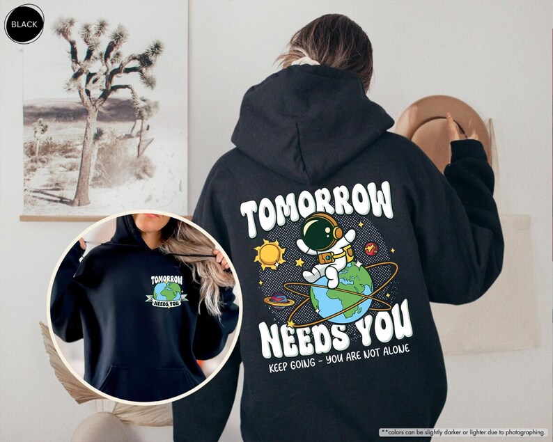 May include: Black hoodie with a graphic on the back showing an astronaut on Earth, the sun, and the text "TOMORROW NEEDS YOU." The front of the hoodie has a smaller graphic with the text "TOMORROW NEEDS YOU."