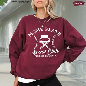 a woman wearing a sweatshirt that says home plate social club