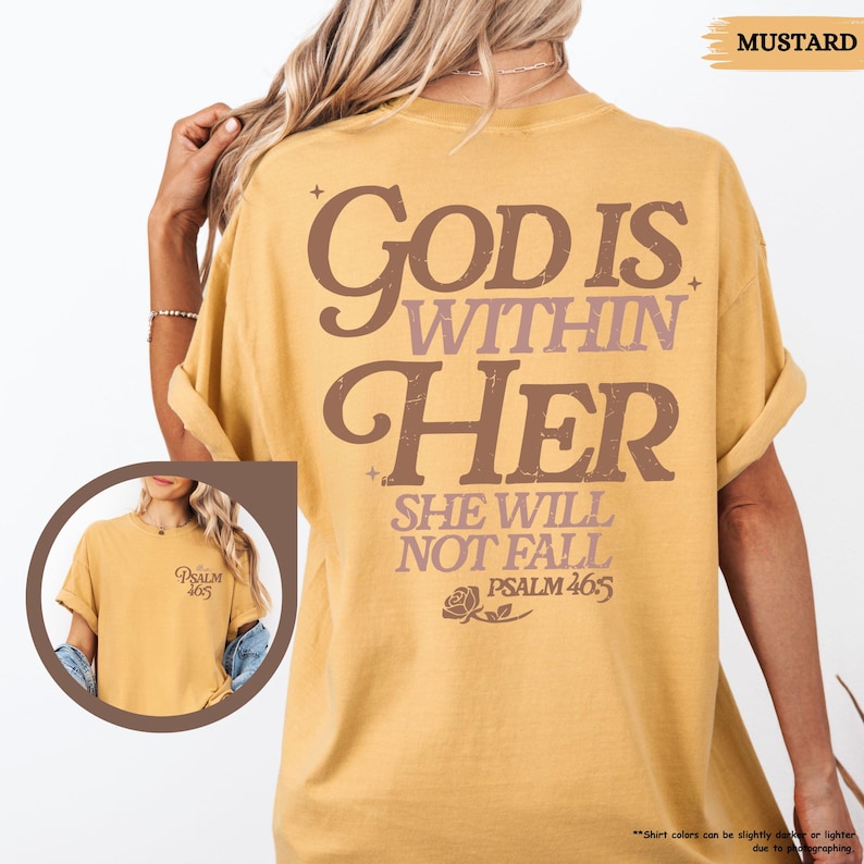 May include: Mustard-colored t-shirt with the text "GOD IS WITHIN HER SHE WILL NOT FALL PSALM 46:5" in brown and purple lettering. A smaller image on the front shows the text "PSALM 46:5".