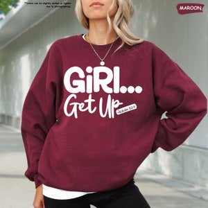 a woman wearing a maroon sweatshirt that says girl get up