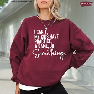 a woman wearing a sweatshirt that says i can't my kids have practice,