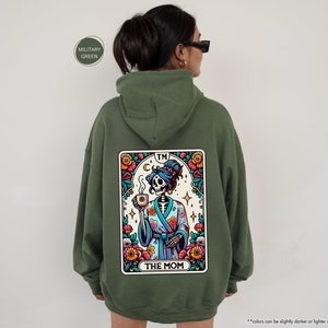 a woman wearing a green hoodie with a picture of a skeleton on it