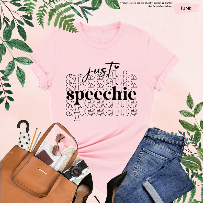 Puede incluir: Camiseta rosa con el texto "just speechie" repetido en un patr&oacute;n apilado. El texto es negro y la camiseta es rosa.