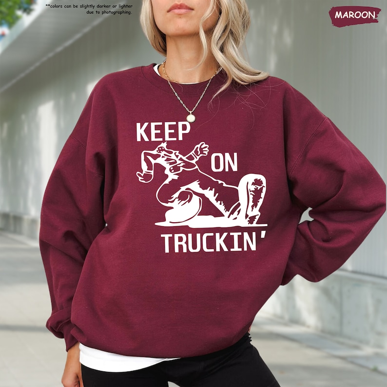 a woman with blonde hair wearing a maroon sweatshirt that says keep on truckin